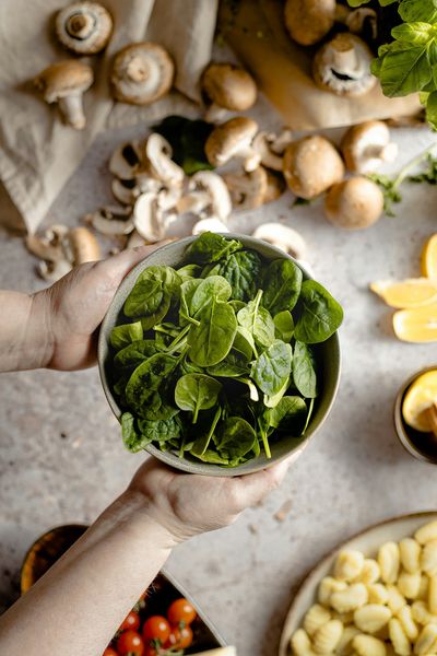 Hands holding a bowl of fresh spinach